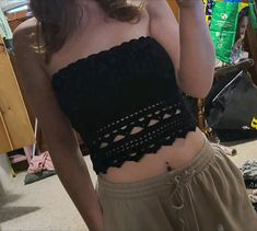 a woman wearing a black crop top and tan shorts is taking a selfie in the mirror