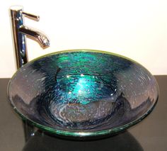 a glass bowl sink sitting on top of a counter next to a faucet