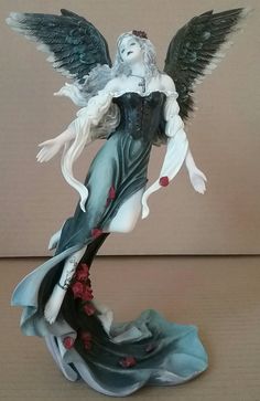 a figurine of a woman with wings and flowers on her body is shown in front of a beige background