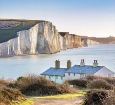 a white house sitting on top of a hill next to the ocean