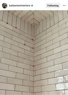 a white tiled wall with red dots on it