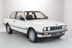 an old white bmw car is parked in a room with a round floor and walls