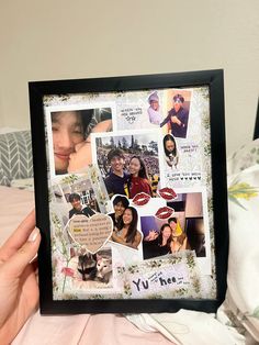 a person holding up a framed photo with many pictures and words on it in front of a bed