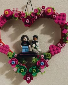 a heart shaped frame made out of legos with flowers and hearts on the wall