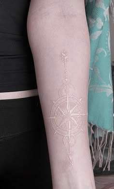 a woman's arm with a compass tattoo on the left side of her body