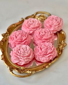 pink flowers are in a gold tray on a white surface