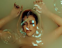 a woman in a bubble bath with bubbles around her head and hands above her head