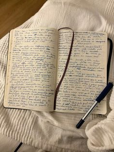 an open notebook with writing on it and a pen laying next to the book,