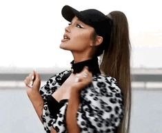 a woman with long hair wearing a black and white outfit, standing in front of a body of water