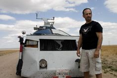a man standing in front of a white vehicle