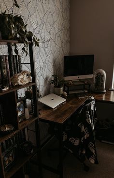 a computer desk with a laptop on top of it next to a book shelf filled with books
