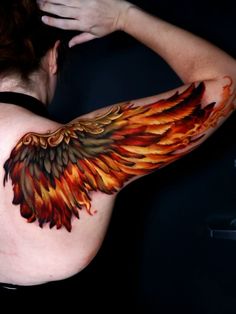 a woman's arm with an orange and red wing tattoo on her left shoulder