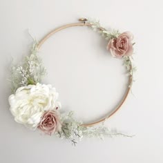 a circular wreath with flowers and greenery on the top is displayed against a white background