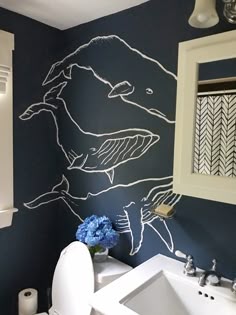 a white toilet sitting next to a bathroom sink under a painting on the wall above it