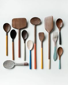 wooden spoons and spatulas lined up on a white surface with different colors