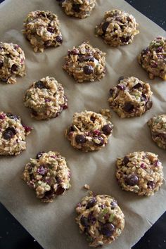 cookies are lined up on a parchmented paper with raisins and chocolate chips