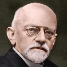 an old photo of a man with glasses and a beard in a black suit jacket