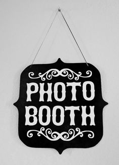 a black and white photo booth sign hanging from a wall