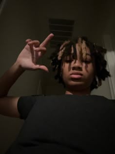 a person with dreadlocks making the peace sign