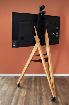 a television on a tripod in front of an orange wall