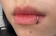 a close up of a woman's lip with a ring on it and her nose