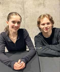 two people sitting at a table with their arms crossed