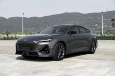 a grey car is parked in front of some mountains