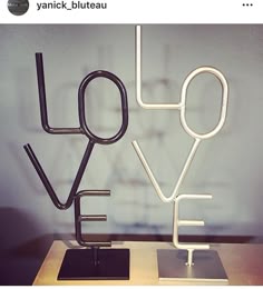 a metal sculpture with the word love spelled in black and white on top of a wooden table