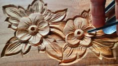 a person carving flowers on a piece of wood with a pair of scissors in their hand