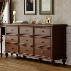 there is a dresser in the room with pictures hanging on the wall and other things