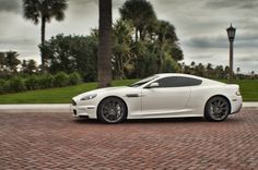 a white sports car parked on the side of a road near palm trees and lampposts
