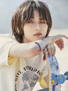 a young boy sitting on top of a skateboard holding his hand out to the side