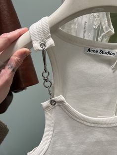 a person holding onto a white shirt with a chain around it's neck and arm