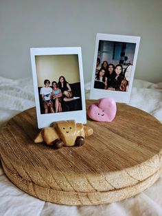 two polaroid frames sitting on top of a wooden tray next to a pink pig