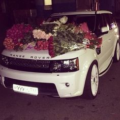 a white range rover with flowers on the hood