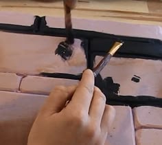 a person using a brush to paint a brick wall with black and white tiles on it