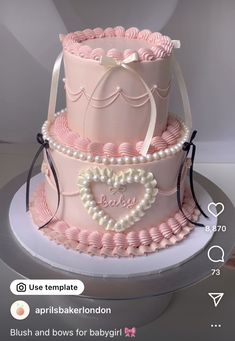 a three tiered pink cake with hearts and pearls on the top is decorated in white icing