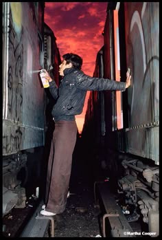 a man standing on train tracks with his hand in the air and holding something up to his face