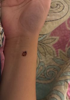 a small ladybug tattoo on the wrist