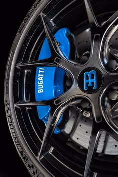 the front wheel of a black car with blue lettering on it's rims