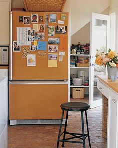 an orange refrigerator with pictures on it in a kitchen next to a counter and stool