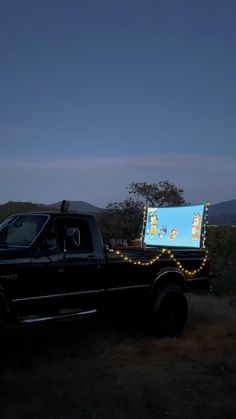 a truck is parked in the dark with a projection screen on it's bed