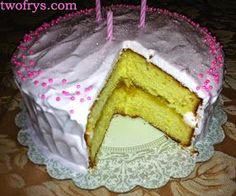 a white cake with pink frosting and two lit candles on it's top