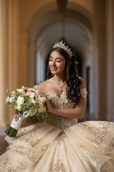 a woman in a wedding dress holding a bouquet and smiling at the camera while wearing a tiara