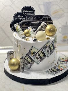 a white cake with money and gold decorations on it's top, sitting on a table