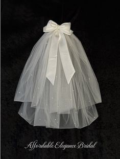 a white wedding dress with a bow on the waist and tulle skirt, made to look like a veil