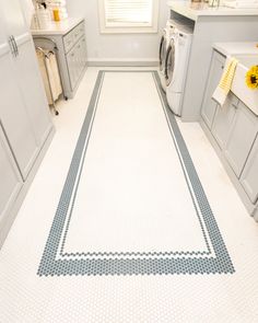a white and blue tiled kitchen floor with yellow flowers on the countertop next to washer and dryer