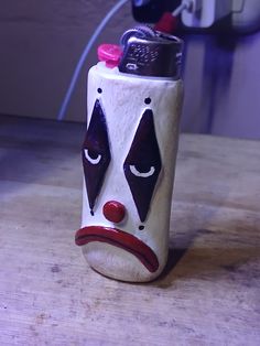 a ceramic jug with a clown face painted on it's side sitting on a table