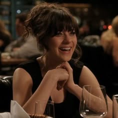 a woman sitting at a table with wine glasses and plates on the table in front of her
