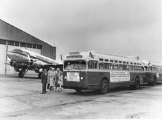an old photo of people standing in front of two buses and one plane on the tarmac